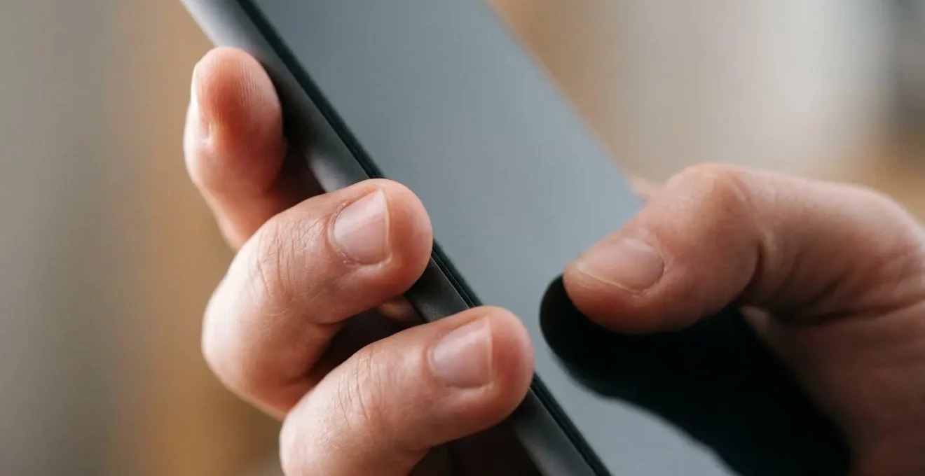 Side view of a hand securely gripping a smartphone showing natural thumb positioning and stable grip