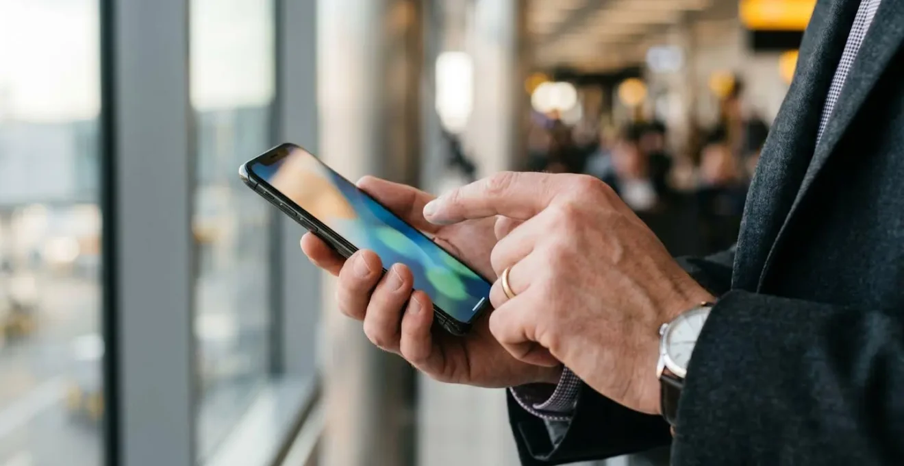 Close-up of hands checking smartphone for transport timing near airport departure