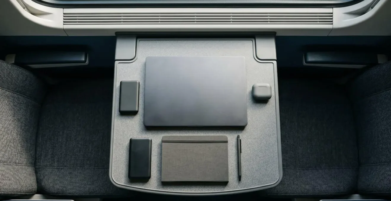 Overhead view of compact workspace on economy train table with device and minimal accessories