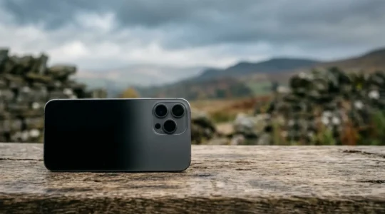 Professional travel photographer comparing smartphone multi-camera system with traditional DSLR camera in UK landscape setting