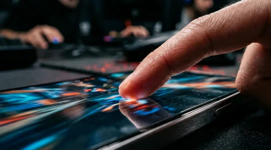Close-up of a gamer's finger making precise contact with a mobile phone gaming screen during competitive gameplay