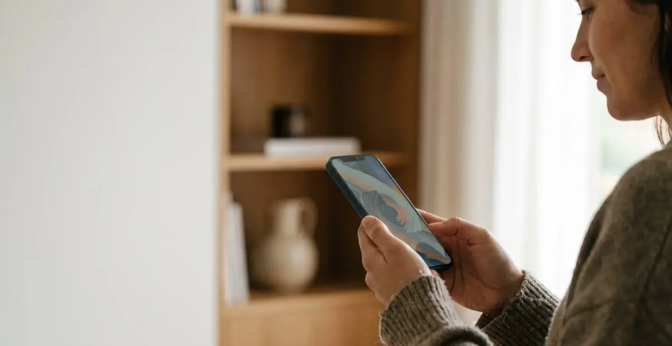 Person holding smartphone examining technical camera specifications with natural lighting creating thoughtful atmosphere