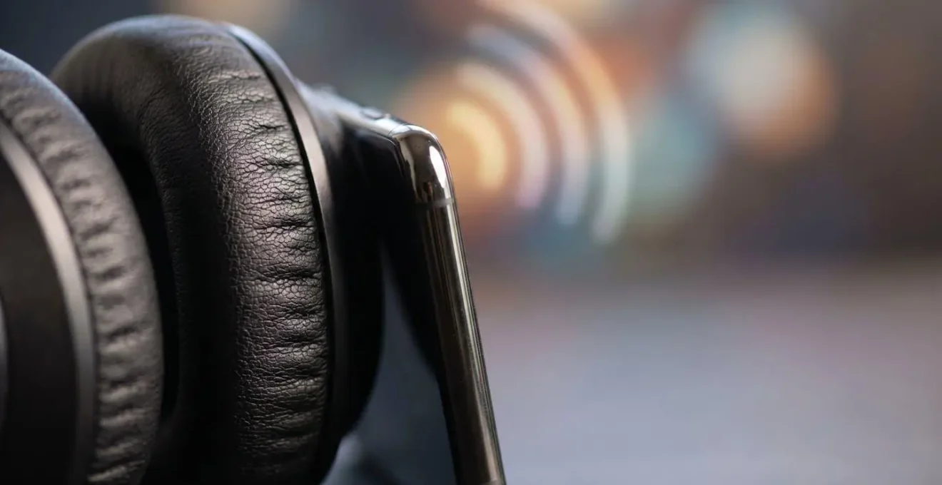Close-up of modern wireless headphones next to smartphone showing audio wave interference pattern with shallow depth of field