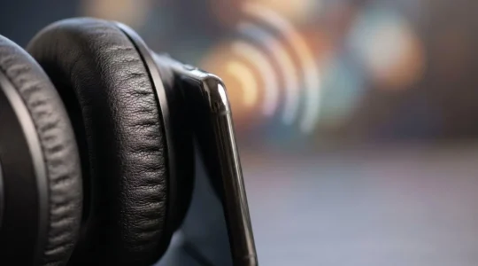Close-up of modern wireless headphones next to smartphone showing audio wave interference pattern with shallow depth of field