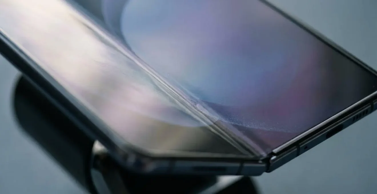 Close-up view of foldable smartphone screen with visible crease line under natural lighting