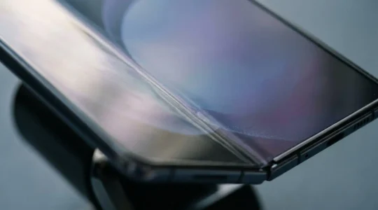 Close-up view of foldable smartphone screen with visible crease line under natural lighting
